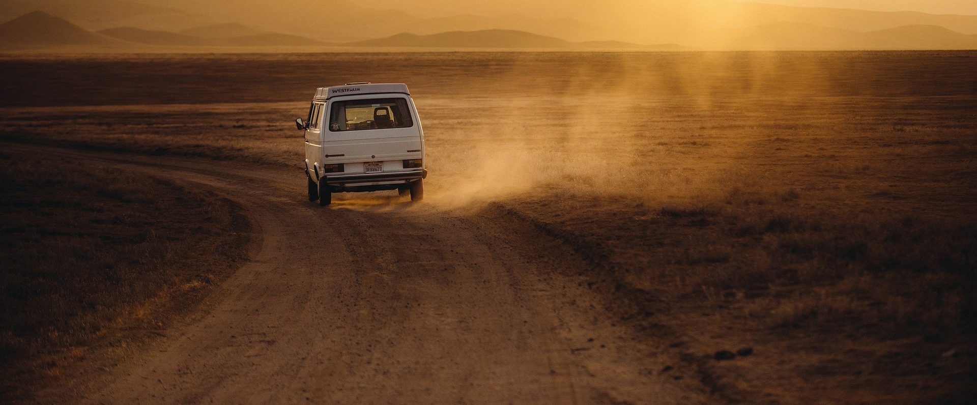 Van de color blanco atravesando una carretera desértica