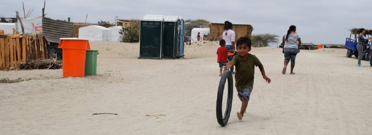 Un niño corre detrás de un neumático por una explanada de tierra