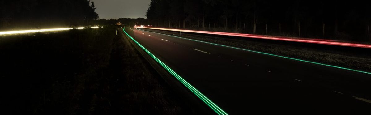 Imagen de una carretera de noche con las señales reflectantes