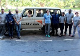 Imagen de un grupo de cooperantes de distintas organizaciones posando delante de un jeep