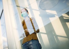 woman with face mask standing by the window