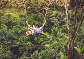 Una joven columpiándose sobre un bosque