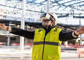 Man engineer using VR goggles on construction site.